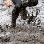 Mud race runner, man running in mud. Runners during extreme obstacle races. Active life and sport concept