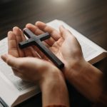 Woman sitting and studying the scriptures.The  wooden cross in t