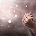 Male hands in praying position with ray