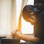 Teenage girl hand with Bible praying in the morning.